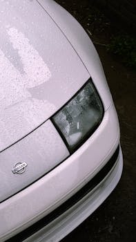 Vertical shot of a white Nissan 300ZX with raindrops on the hood, captured outdoor in Santiago de Querétaro, Mexico.
