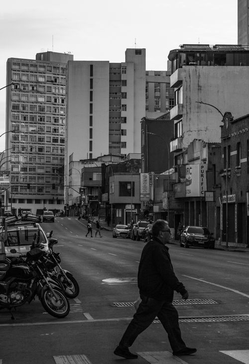 Free Black and white urban street view with a man crossing the road in a bustling city. Stock Photo