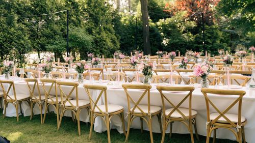 Free Charming outdoor wedding setup with elegantly decorated tables and chairs in a garden setting. Stock Photo
