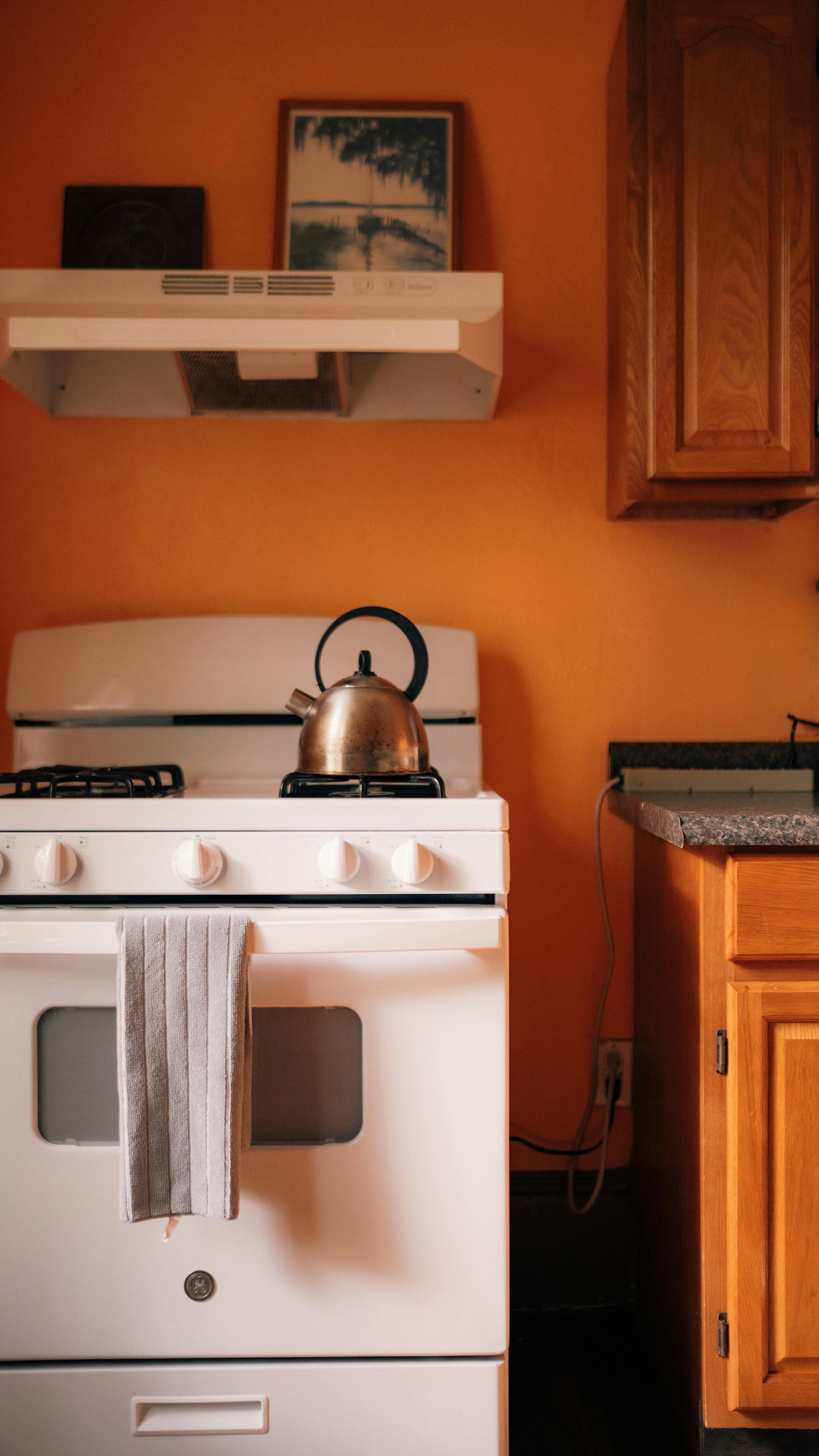 A white stove with a tea kettle on top of it