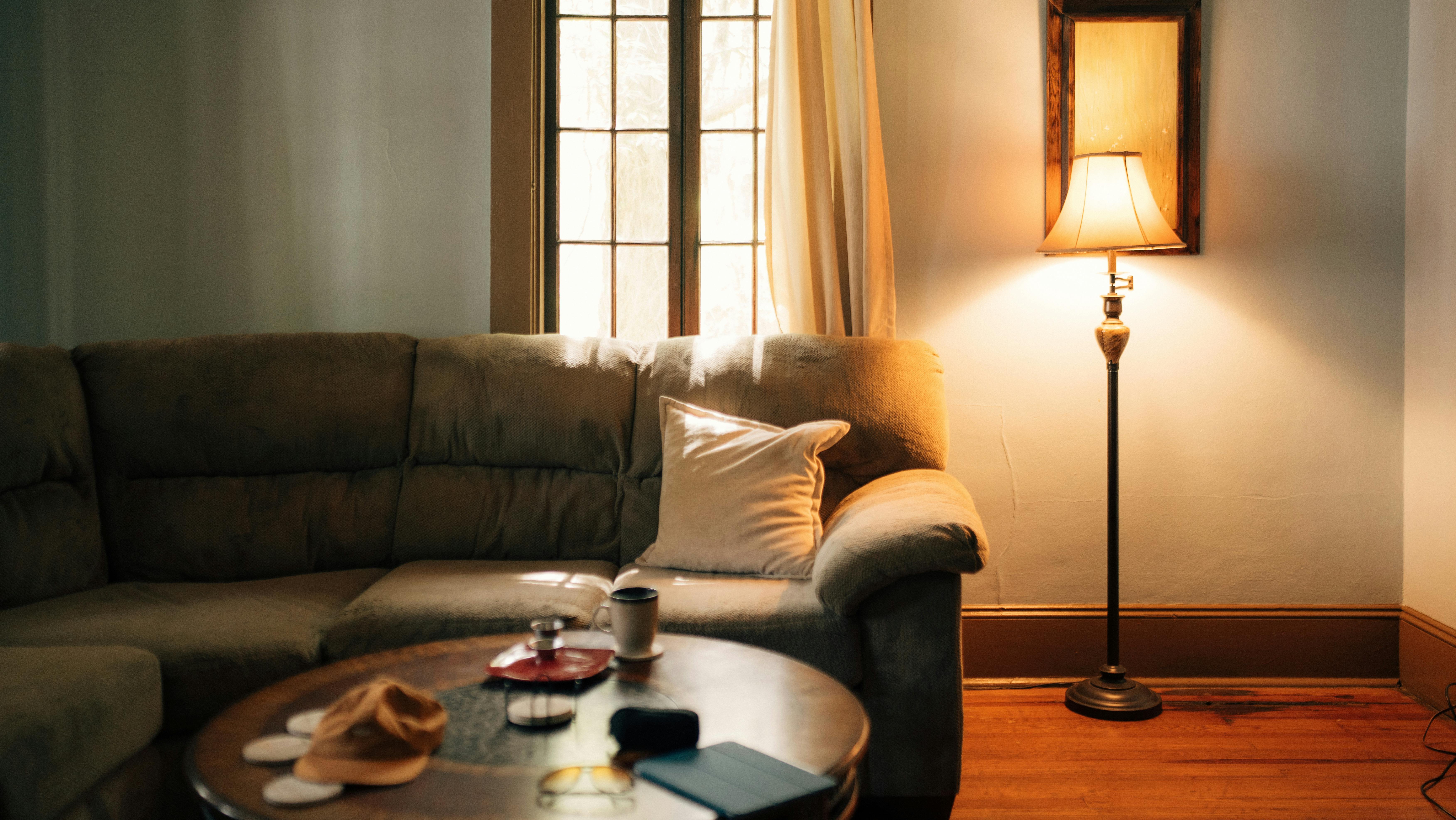 Salon z tapczanem i lampą podłogową w ciepłej barwie światła ustawioną bez odblasków na ekranie