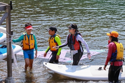 Children and instructor learning windsurfing by the lake. Perfect outdoor recreation for a sunny day.