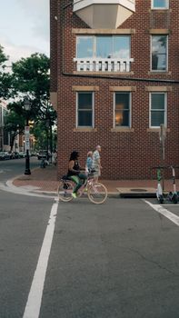 Cyclists riding by brick building on a Washington, DC street corner, capturing urban life.