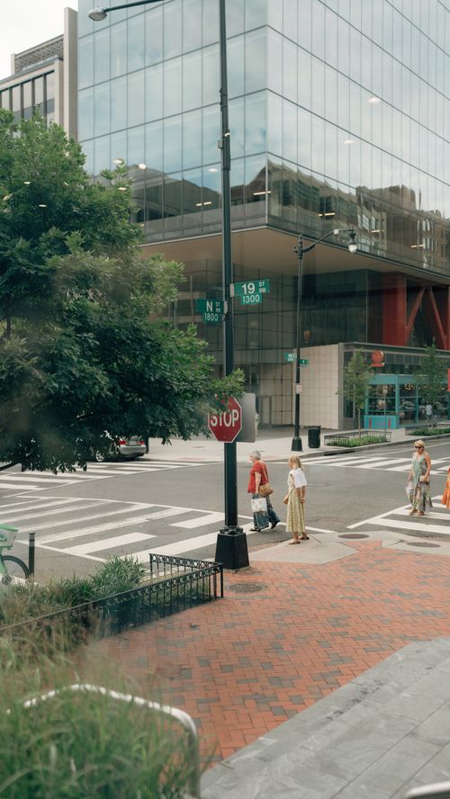 Free Pedestrians crossing a city intersection in Washington, DC with modern architecture. Stock Photo