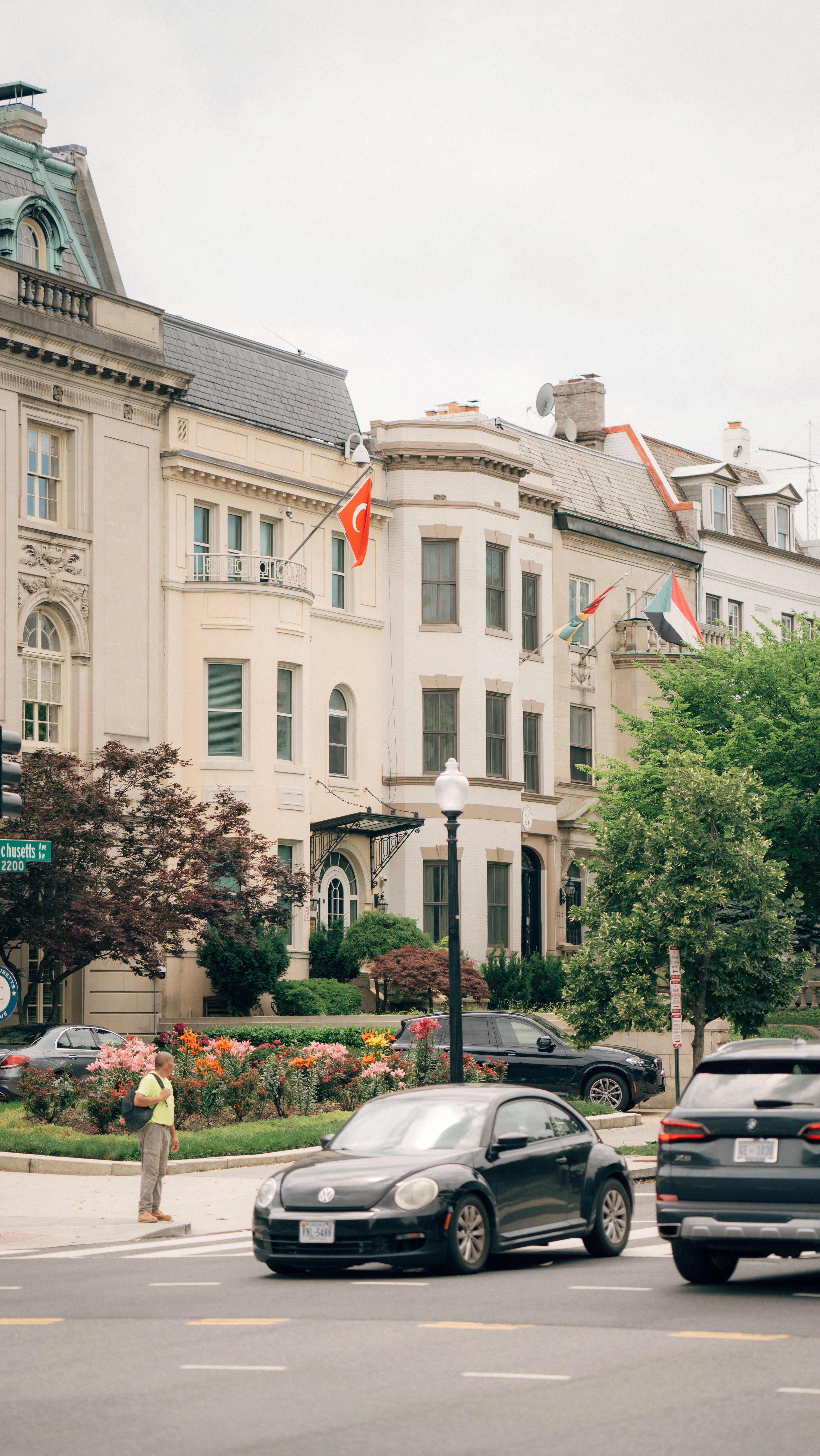 Busy city street in Washington, DC featuring cars, historic buildings, and national flags on a summer day.