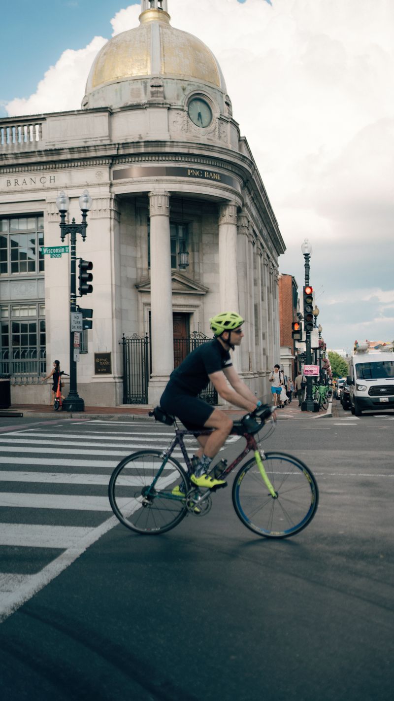 Cyclist riding past a historic bank building in Georgetown, Washington DC