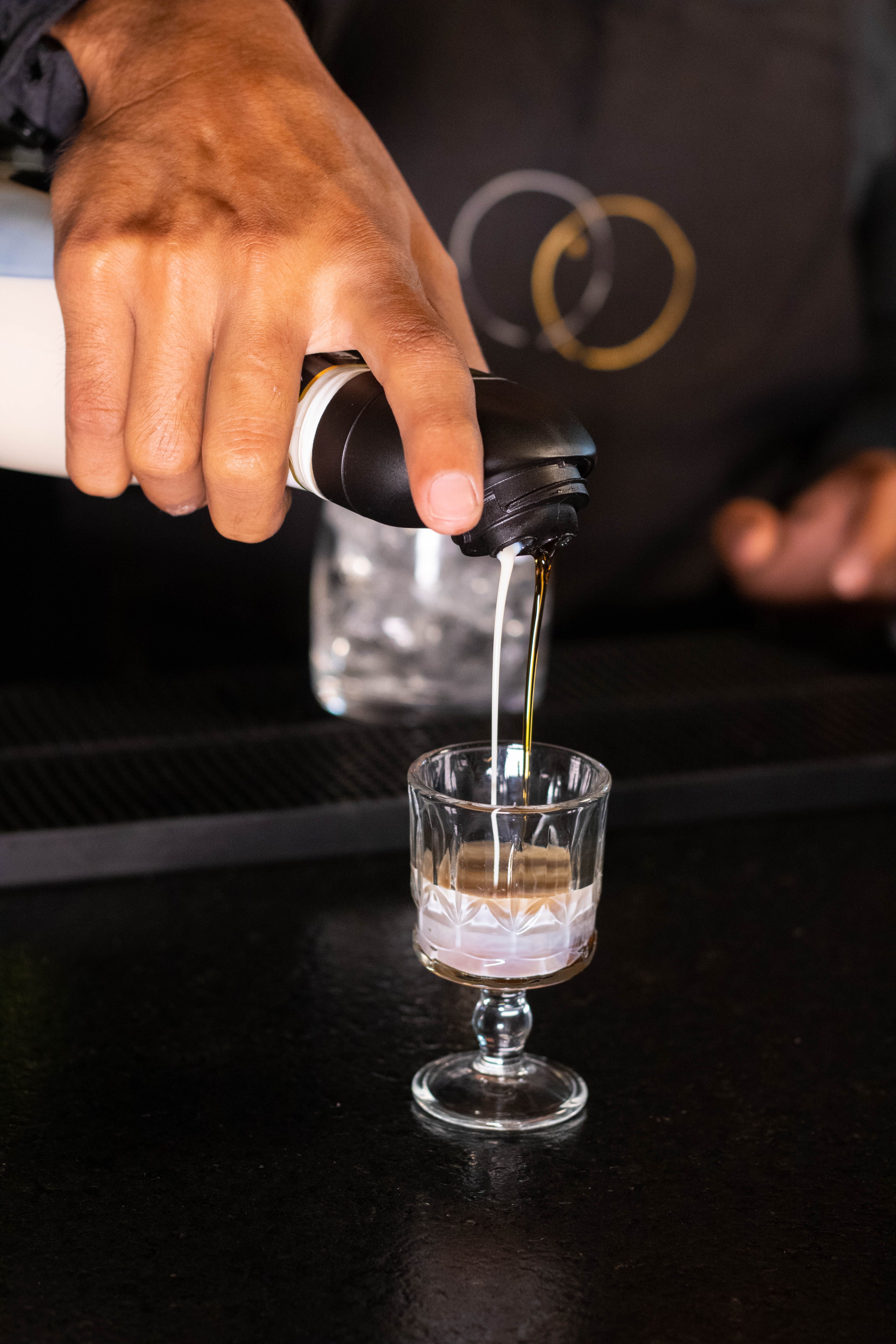 Close-up of a bartender pouring a drink into a glass at a bar.