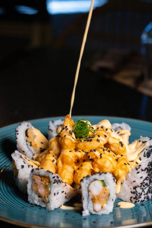 Free Mouthwatering close-up of sushi rolls topped with creamy sauce and sesame seeds. Stock Photo