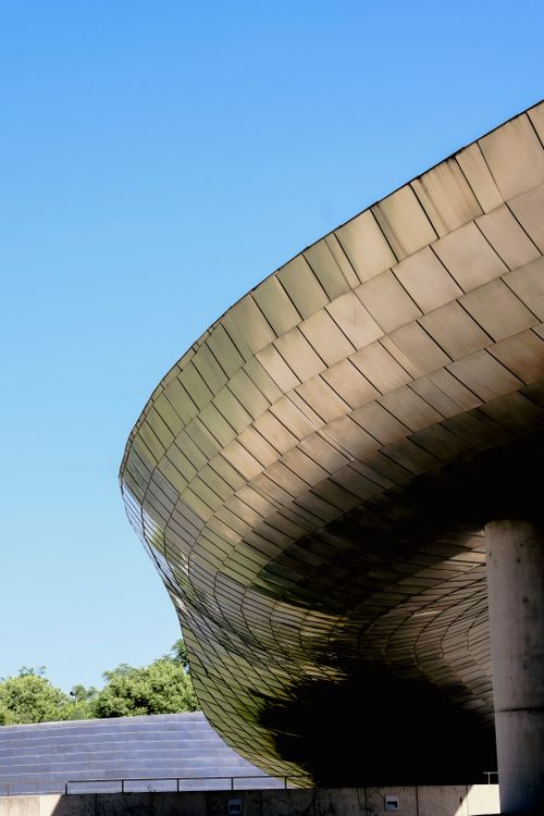 Free A sleek, modern architectural structure beneath a clear blue sky, showcasing contemporary design. Stock Photo