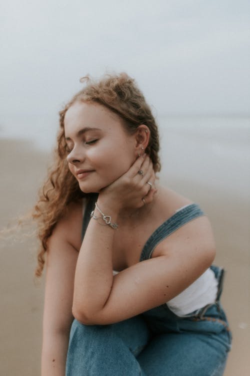 Free A girl sitting on the beach with her hair in a bun Stock Photo