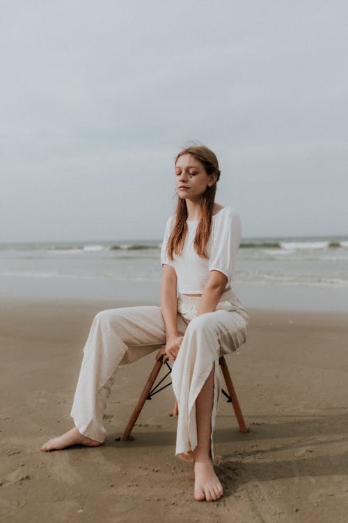 Free A woman sitting on a chair on the beach Stock Photo