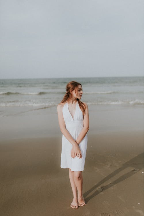 A woman in a white dress standing on the beach