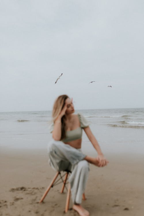 Free A woman sitting on a chair on the beach Stock Photo