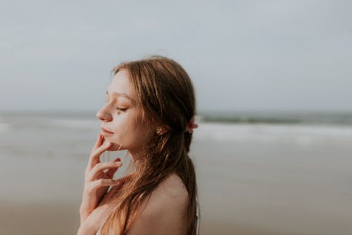 Free A woman is standing on the beach and looking at the ocean Stock Photo