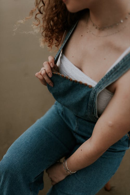 A woman in overalls sitting on a bench