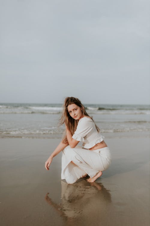 A woman in white sitting on the beach