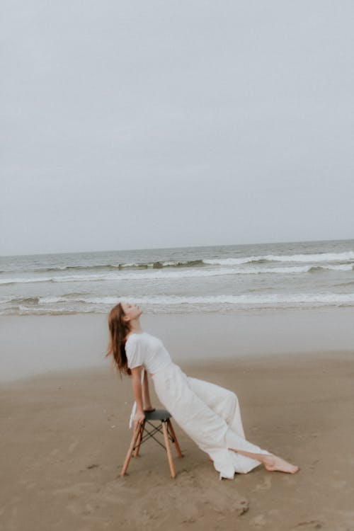 A woman sitting on a chair on the beach