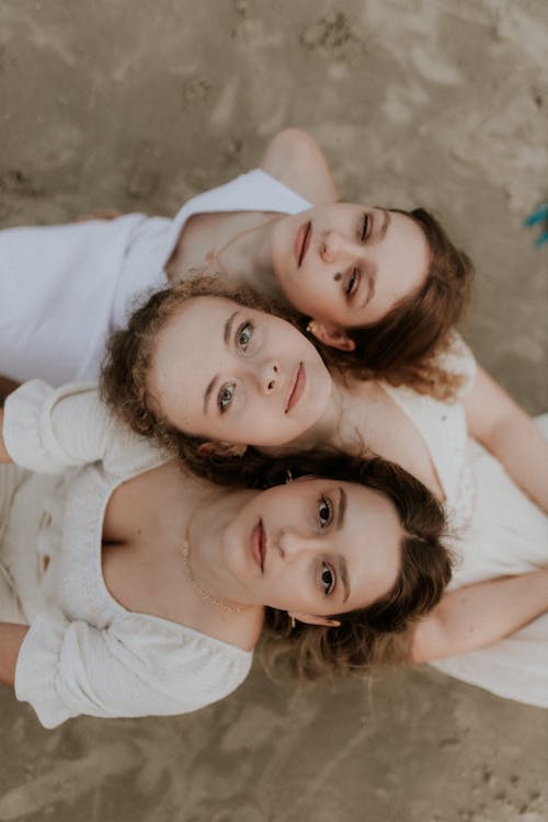 Free Three young women laying on the beach in white dresses Stock Photo