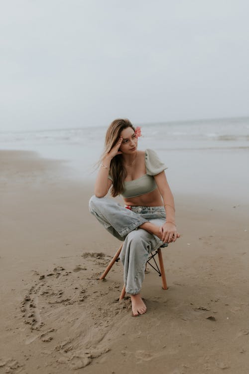 Free A woman sitting on a chair on the beach Stock Photo