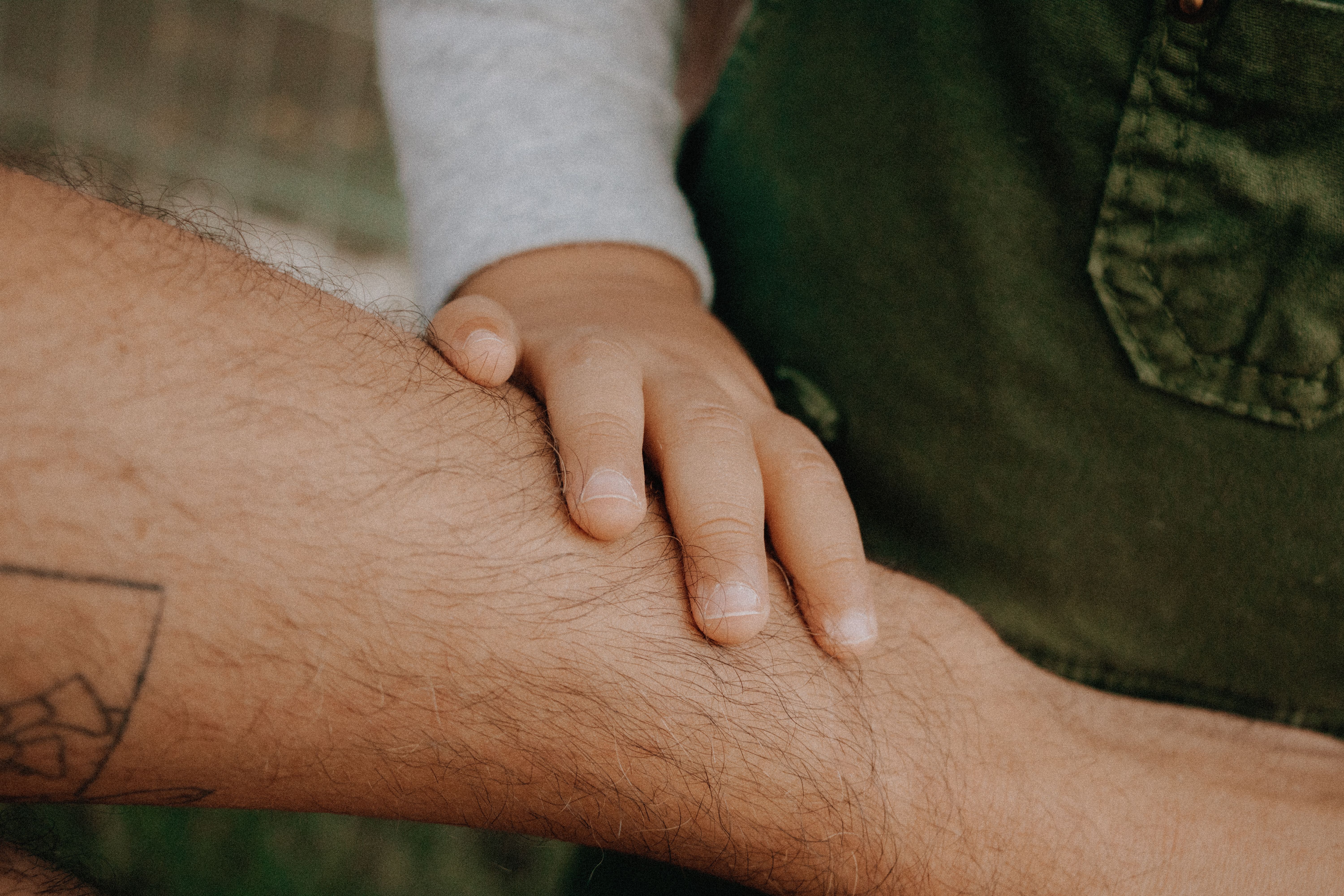 Close-up of a child's hand gently touching an adult's forearm, symbolizing connection.