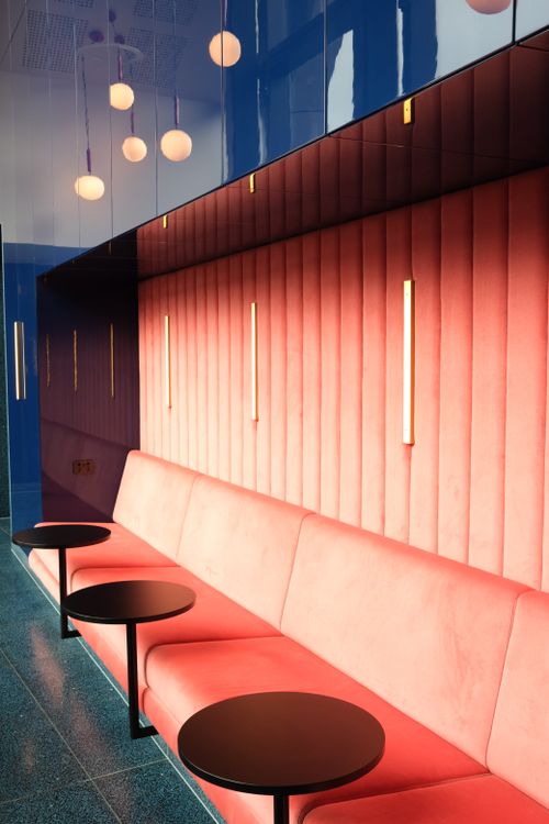 Free Sleek and vibrant café interior with red seating and stylish round tables. Stock Photo