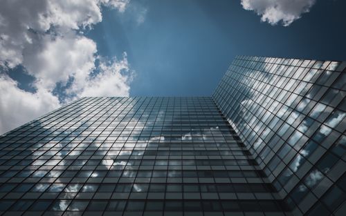 Free Low angle view of a glass skyscraper in Hamburg reflecting clouds in a clear sky. Stock Photo