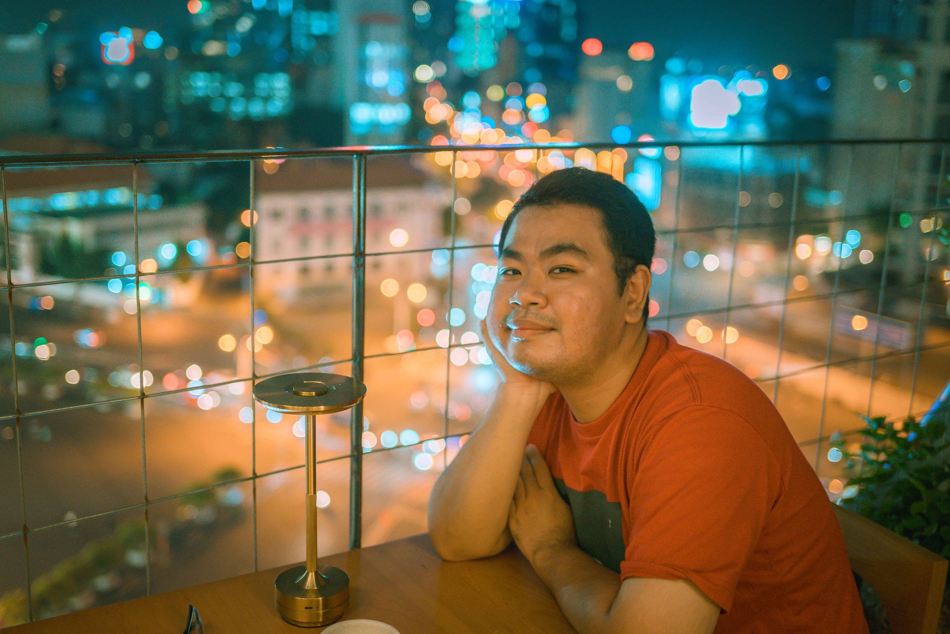 Relaxed night out on a rooftop in Ho Chi Minh City, vibrant cityscape in the background.