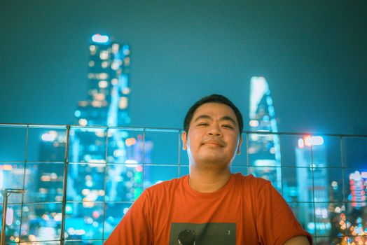 Man posing with Ho Chi Minh City's skyline beautifully illuminated at night.