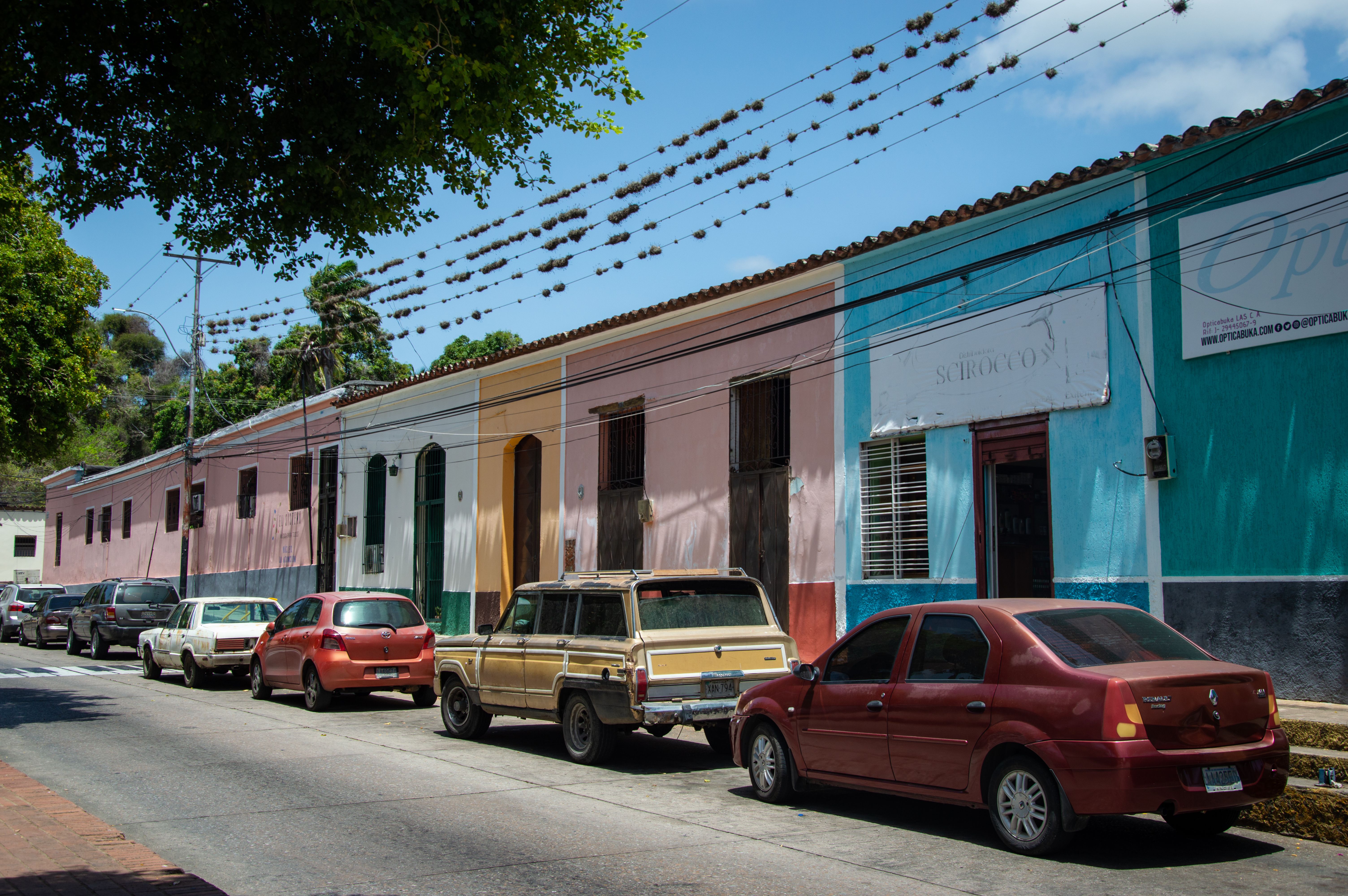 An electric car parked beside a hotel wall in Honduras with a portable charging cable running to a socket