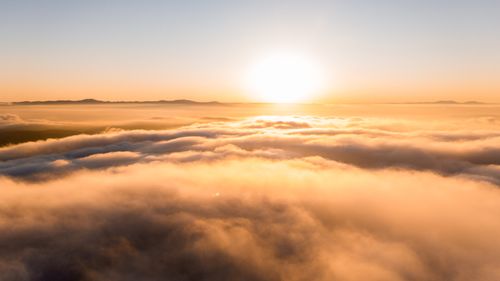Free Beautiful sunrise scene with the sun rising above the clouds, captured from an aerial perspective. Stock Photo
