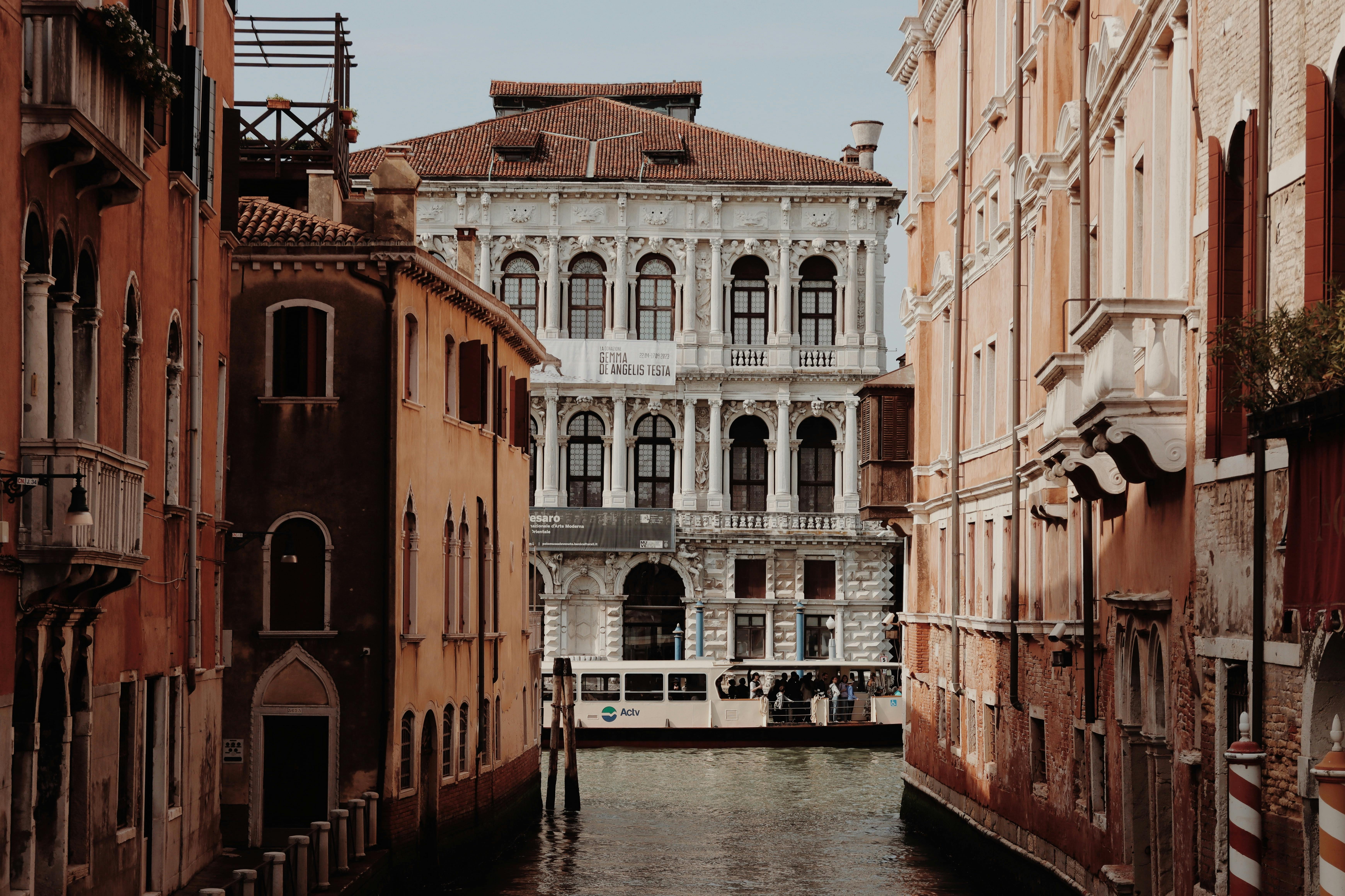 Discover the architectural beauty of Ca' Pesaro Palace along a serene Venice canal with a passenger boat.