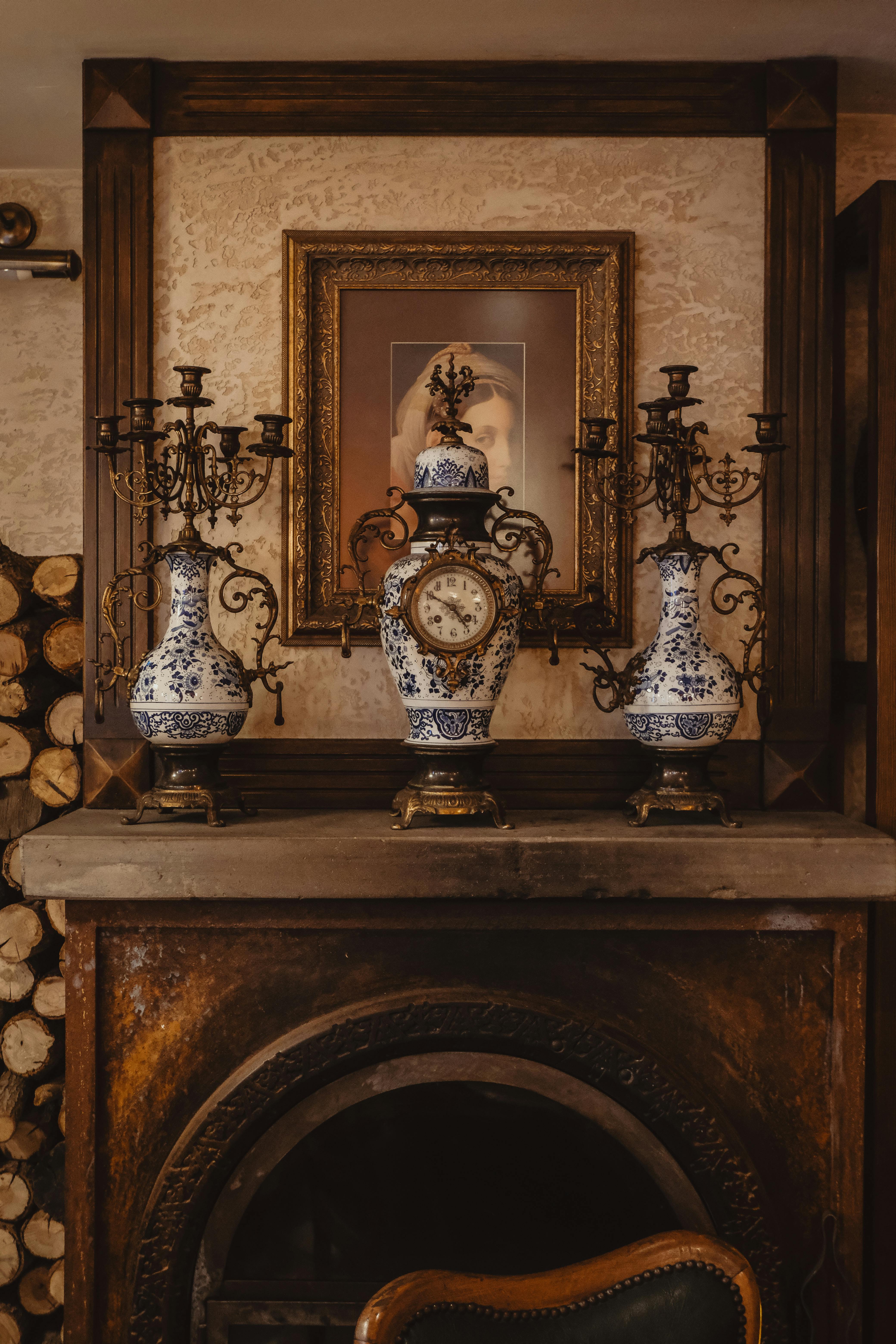 Vintage mantelpiece with blue vases, ornate clock, and framed art creating a classic ambiance.