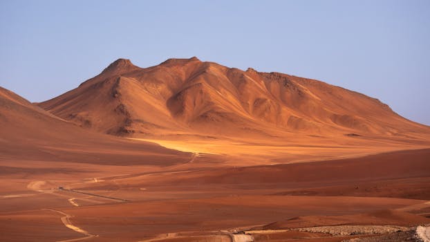 Stunning view of the Atacama Desert with rolling dunes and mountains under clear blue skies.