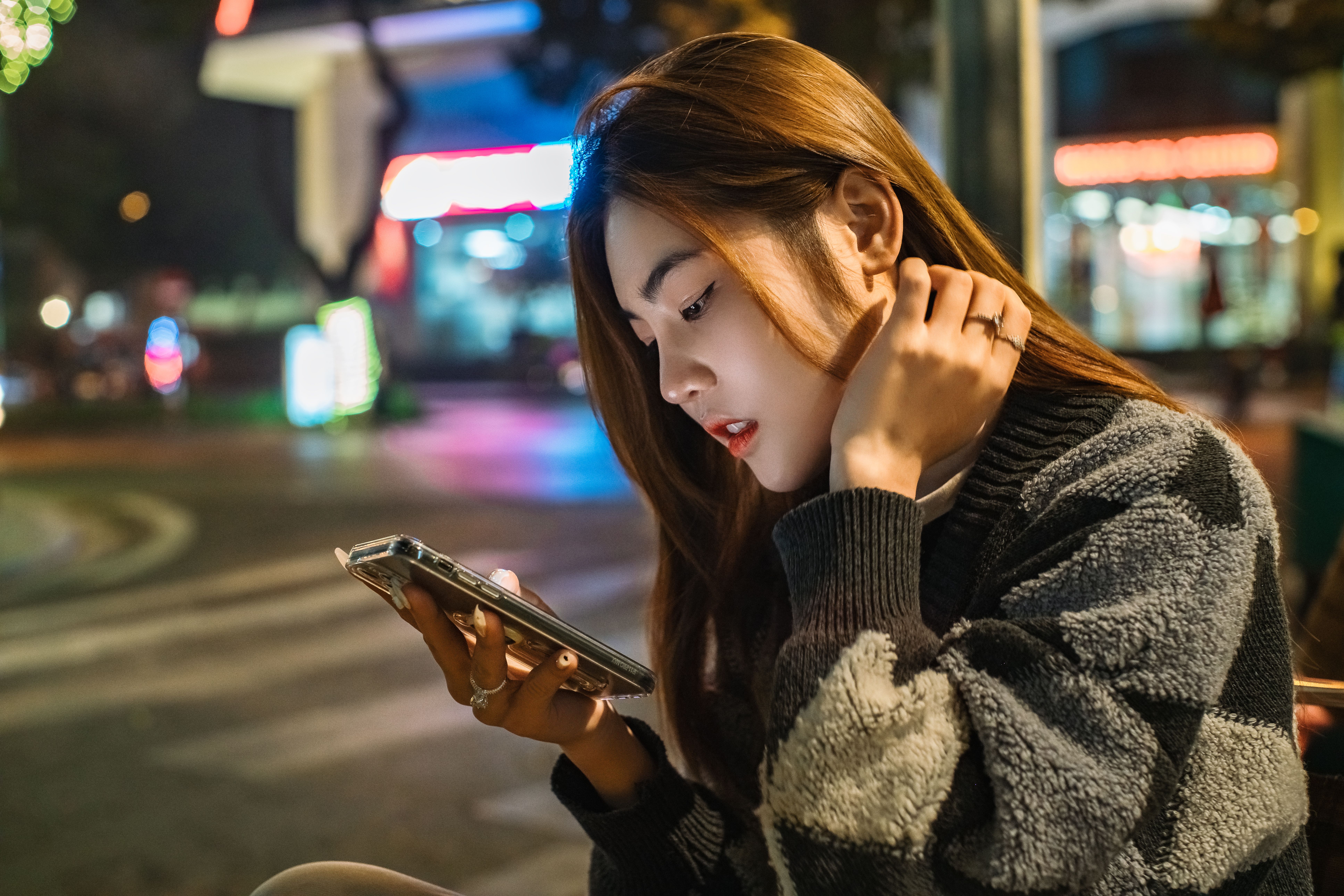 都市街頭上專注滑手機的年輕女生