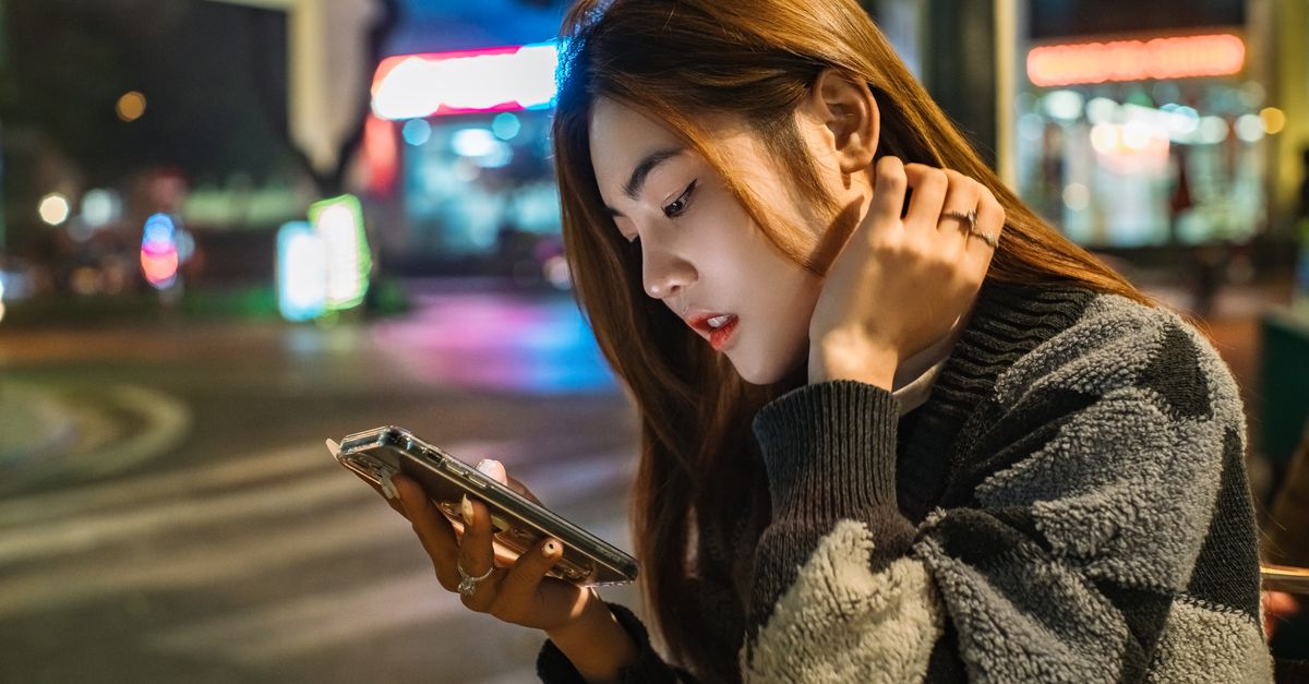 都市街頭上專注滑手機的年輕女生