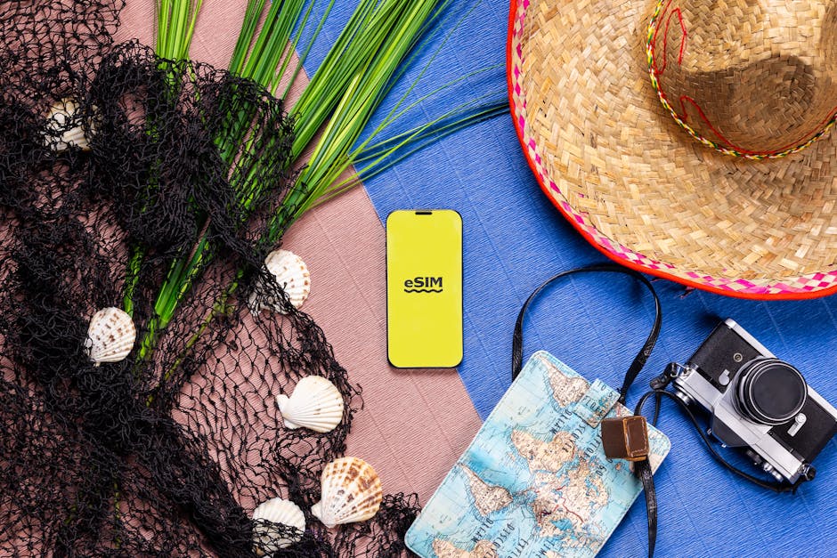 A vibrant flat lay of travel items featuring a smartphone with eSIM, hat, camera, and map.