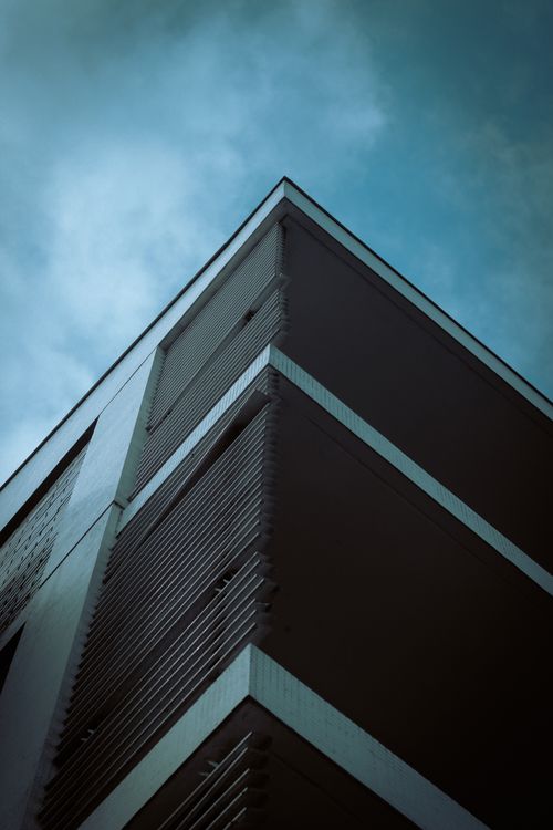 Free Low-angle view of a modern office building against a dramatic cloudy sky. Stock Photo