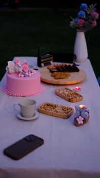 A serene evening party setup with pink cake, cookies, and decor in Gaziantep, Türkiye.
