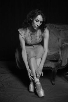 Black and white portrait of a ballet dancer sitting gracefully in a vintage armchair.