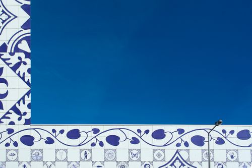 Free Artistic blue and white ceramic tile wall against a clear sky, with decorative floral patterns. Stock Photo