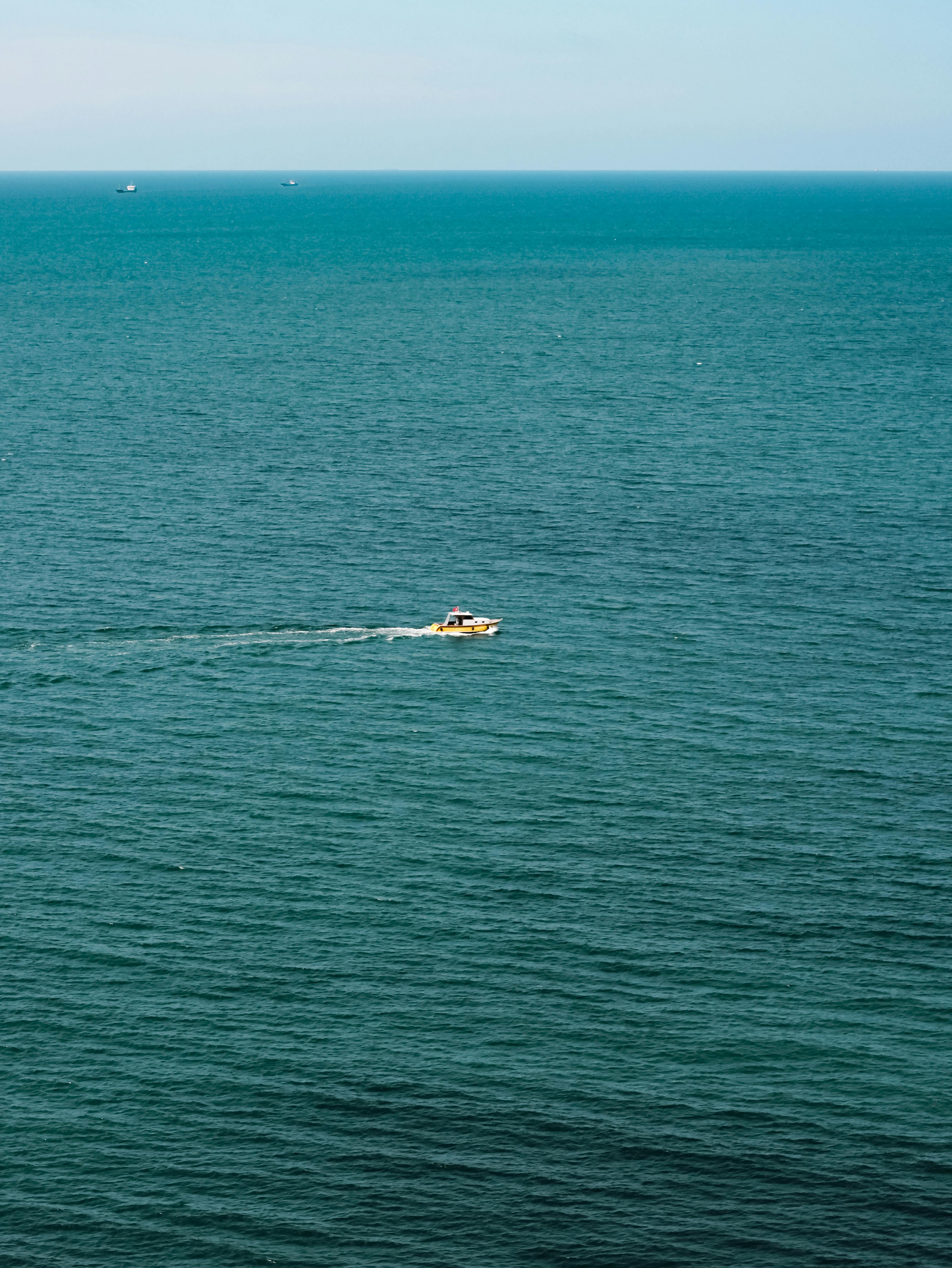 Motorboat cruising through tranquil blue ocean, captured from above on a clear day.