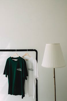 Modern minimalist room featuring green and white T-shirts hanging beside a white lamp.