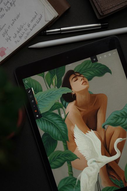 Top view of a tablet displaying an artistic illustration of a woman and a bird among leaves. - The Future of AI in Creative Industries: My Vision for Human-AI Collaboration.