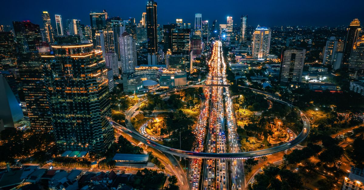 Aerial view of Central Jakarta's skyline and traffic-lit streets at night.
