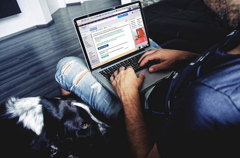 Mann sitzt, während er einen Laptop benutzt. | Quelle: Pexels