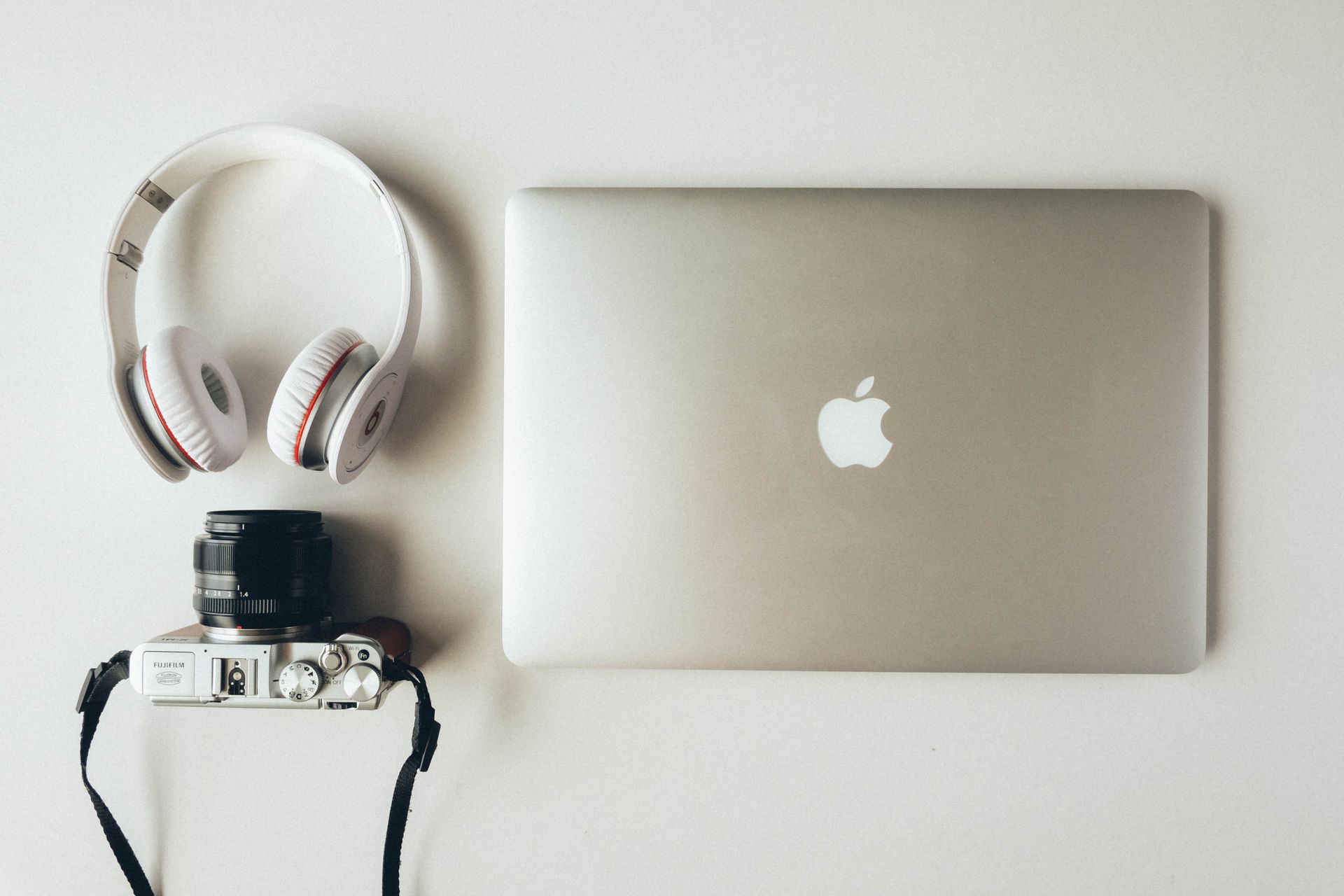 Silver Macbook Beside Headphones and Camera