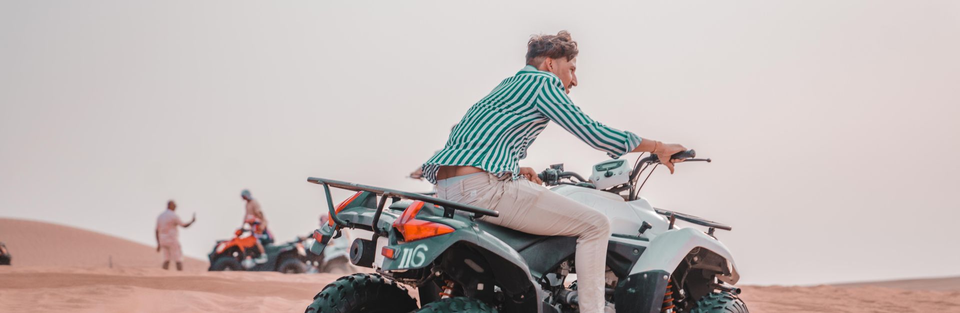 Man on an ATV enjoying a thrilling ride across desert sands.