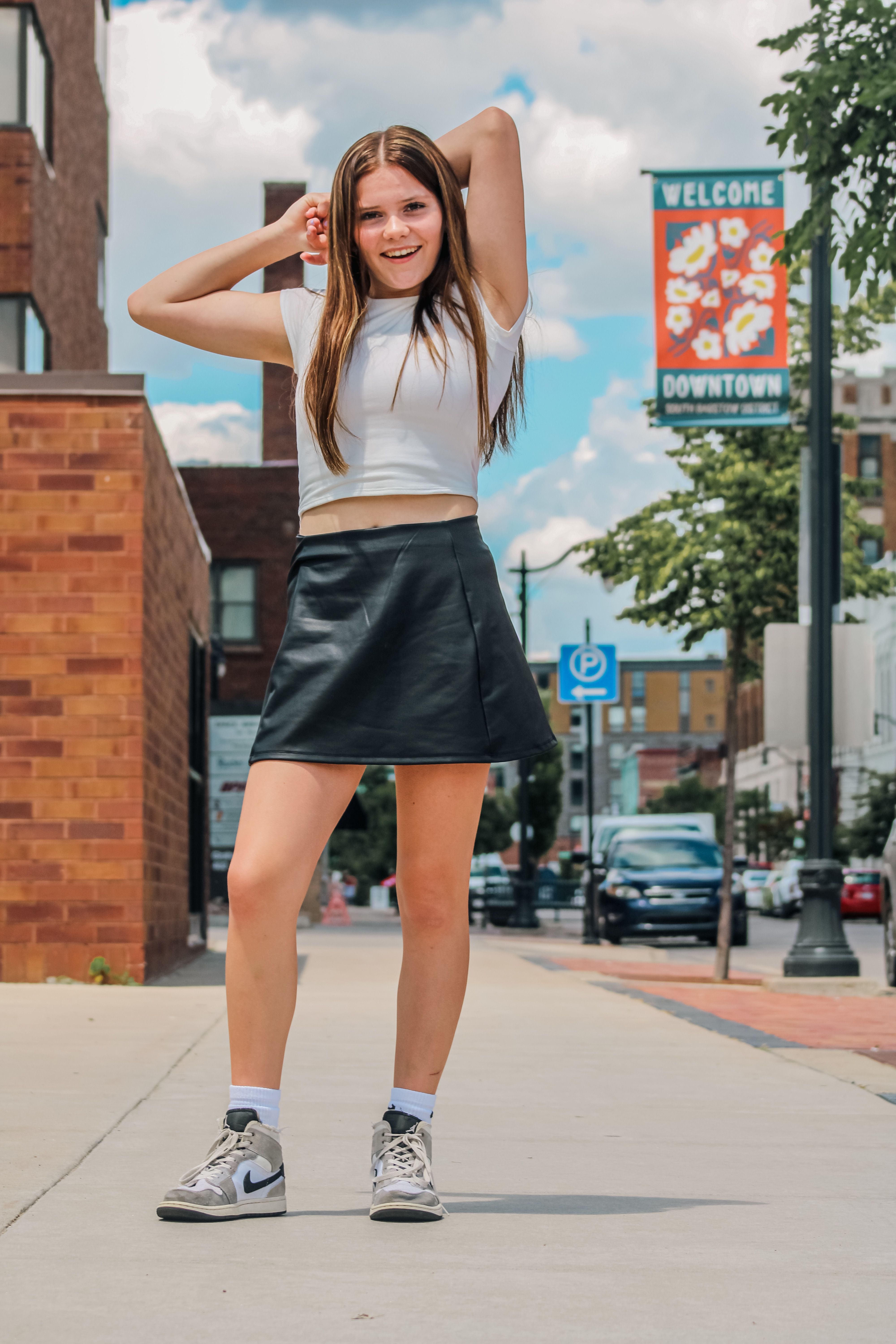 Teenager in stylish attire posing confidently on downtown street, embracing urban fashion.