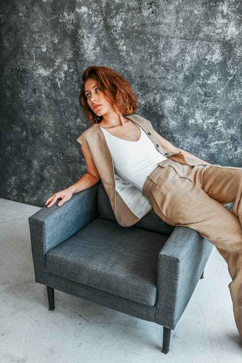 A woman in a tan suit sitting on a gray chair