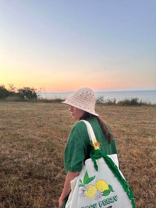 Free Young woman with a cotton bag in a rural meadow during sunset. Stock Photo